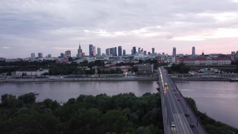 Cinematic-drone-footage-of-Warsaw-skyline-with-vistula-river-and-bridge-filled-with-traffic-flowing