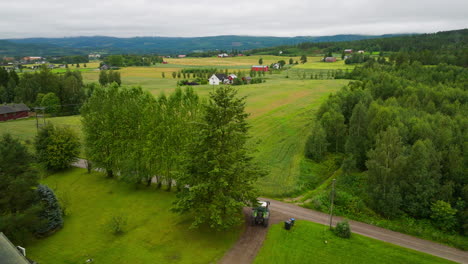 Tractor-Agrícola-Conduciendo-Por-Una-Carretera-Rural-Con-Un-Paisaje-Natural-Siempre-Verde-En-El-Sureste-De-Noruega