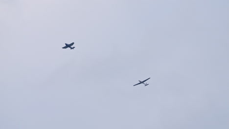 Small-plane-towing-Swift-S-1-glider-in-sky,-handheld-view