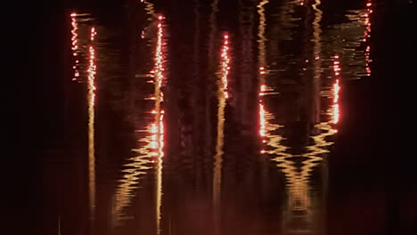 Comet-fireworks-reflected-in-water-create-abstract-patterns-in-black