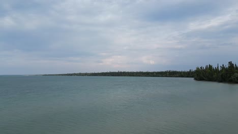 A-moving-aerial-drone-shot-of-Clearwater-Lake-from-Sunset-Beach-on-the-outskirts-of-The-Pas-area-during-the-Summer-of-2023-during-a-cloudy-day