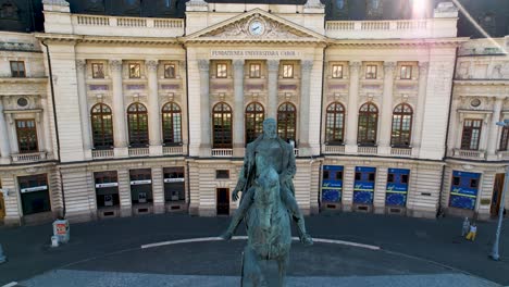 Luftaufnahme-Der-Statue-Von-König-Carol-I.-Und-Der-Zentralen-Universitätsbibliothek-Im-Hintergrund-In-Bukarest,-Rumänien,-Mit-Sonnenstrahlen,-Die-über-Dem-Historischen-Gebäude-Platzen