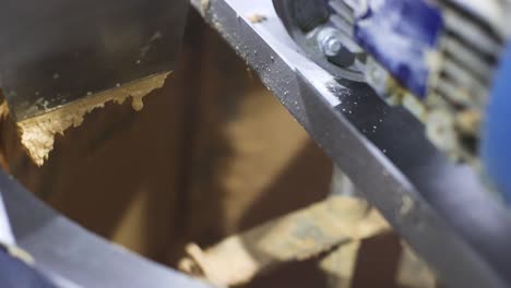 Slow-motion-scene-of-peanut-butter-being-creamed-into-a-storage-tank-at-a-peanut-butter-processing-plant