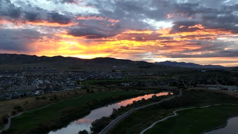 Golden-sunset-over-a-golf-course-reflecting-off-a-river---aerial-panorama
