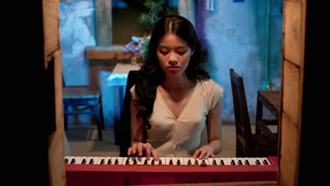Asian-girl-playing-keyboard-at-the-window,-static