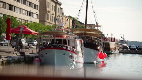 Excursion-boat,-crew-and-passengers-docked-at-Pula-Marina-as-vehicles-go-past