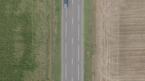 Vehículos-Circulando-Por-La-Carretera-Entre-Campos-Agrícolas-En-Domnesti,-Rumania---Antena-Arriba-Hacia-Abajo