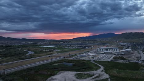 Colorful-sunset-beyond-a-stormy-sky-in-a-suburban-valley---aerial-flyover