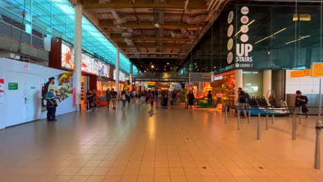 Passing-by-Schiphol-International-Airport-terminal-with-passengers-and-shops