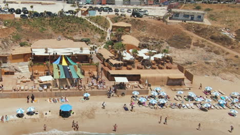 Group-of-tourist-relaxing-on-sunbed-in-front-of-clear-ocean-and-sandy-beach-in-Batroun,-Lebanon