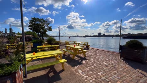 Terrace-of-yellow-wooden-picknick-tables-in-the-sun-on-IJ-river-in-Amsterdam-Noord