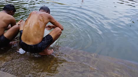 Devoto-Bañándose-En-El-Sereno-Lago-Sagrado-De-Pushkar-En-El-Centro-De-La-Ciudad-Durante-El-Día-Desde-Un-ángulo-Plano.-El-Vídeo-Se-Toma-En-Pushkar,-Rajasthan,-India,-El-13-De-Agosto-De-2023.