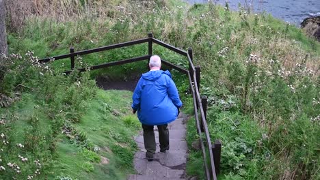 Walking-down-the-hill-from-Dunnottar-Castle,-Scotland,-United-Kingdom