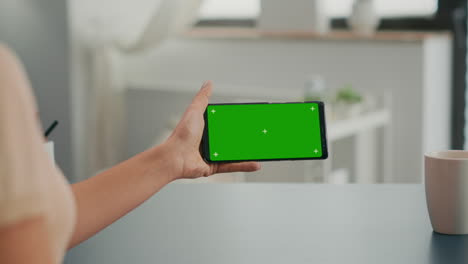 Freelancer-holding-smartphone-with-mock-up-green-screen