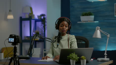 African-social-media-woman-looking-in-laptop-talking-at-microphone