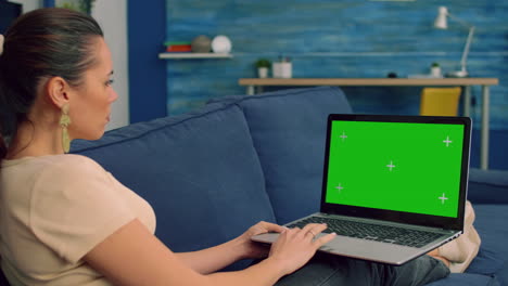 Tracking-shot-of-freelencer-woman-typing-on-mock-up-green-screen-chroma-key-laptop-computer