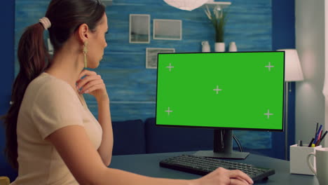 Caucasian-female-searching-on-computer-with-mock-up-green-screen-chroma-key-display
