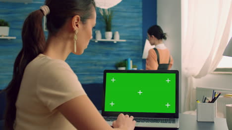 Woman-typing-on-computer-laptop-with-mock-up-green-screen-chroma-key-display