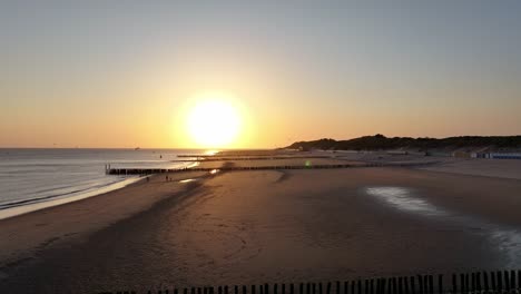 Wunderschöner-Sonnenuntergang-An-Einem-Sandstrand-Mit-Ruhigem-Meer-Und-Pier