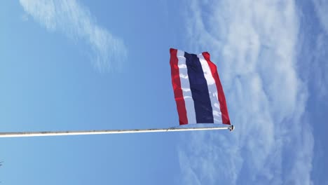 Vertical-of-Waving-the-Kingdom-of-Thailand-flag-on-a-pole-with-blue-sky-and-white-clouds-in-the-background