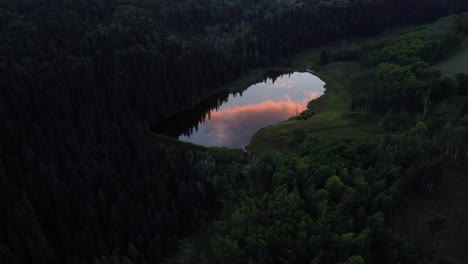 Red-golden-hour-clouds-are-reflecting-in-tiny-forest-lake