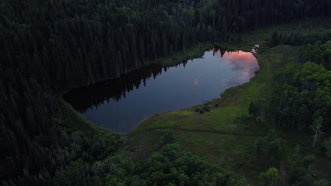 Drone-shot-of-the-mirror-like-surface-of-the-lake-beautifully-reflects-the-vivid-red-clouds-above