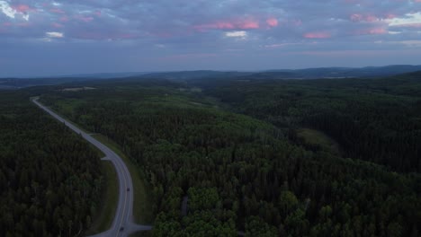 Drone-shot-of-the-highway-in-the-middle-of-the-endless-forest-in-summertime