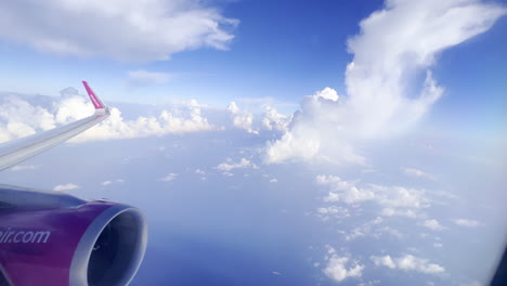 Airplane-wing-and-blue-sky-with-fluffy-clouds-seen-from-high-altitude