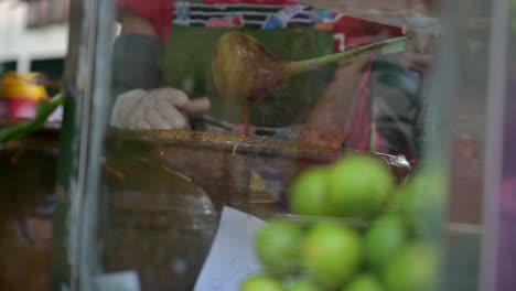 Half-body-shot-of-a-local-street-food-vendor-mixing-and-pounding-Somtam-papaya-salad-using-a-mortar-and-pestle,-in-a-roadside-restaurant-in-the-streets-of-Bangkok,-Thailand