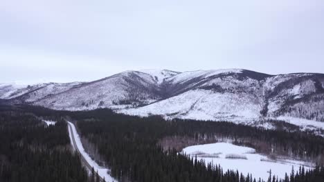 Slow-Orbit-of-Alaska-Snow-Capped-Hill,-with-Small-Frozen-Pond-on-Roadside,-Chena-Hot-Springs-Road