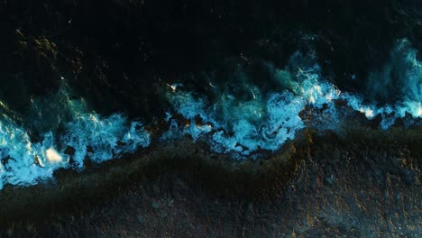Drone-top-down-ascend-as-whitewash-crashes-and-shoreline-glows-and-glimmers