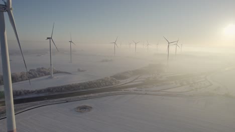 Close-up-flyby-of-a-wind-turbine-in-wind-farm-in-snowy-hazylandscape-near-German-Highway