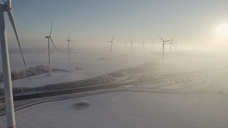 Nahaufnahme-Eines-Vorbeiflugs-Einer-Windkraftanlage-Im-Windpark-In-Verschneiter,-Dunstiger-Landschaft-In-Der-Nähe-Der-Deutschen-Autobahn