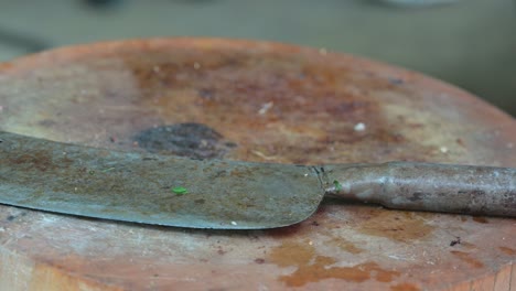 Some-people's-footsteps-can-be-seen-at-the-back-side-of-the-frame-behind-the-chopping-with-a-butcher's-knife-on-top-of-it,-in-a-restaurant-in-Bangkok,-Thailand