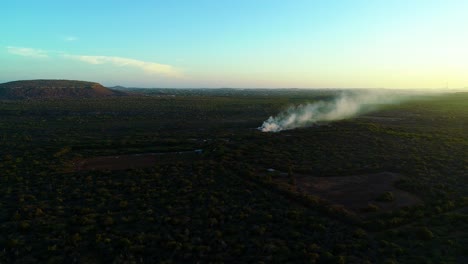 Aerial-panoramic-overview-of-smoke-plume-from-fire-rising-into-sky-in-dry-arid-landscape