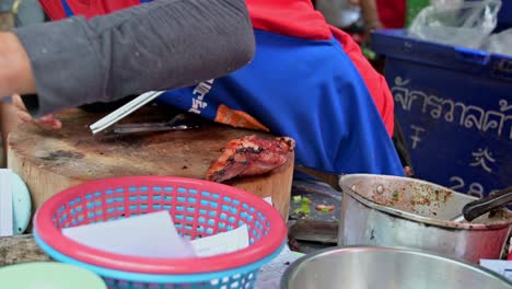 Local-street-food-vendor-quickly-mixing-a-famous-Thai-Northeastern-food-Laab,-a-mixture-of-minced-meat,-condiments-and-spices-in-a-roadside-restaurant-in-Bangkok,-Thailand