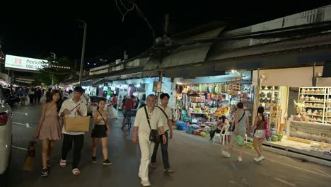 Bei-Einem-Spaziergang-Durch-Den-Chatuchak-Wochenendnachtmarkt-Sind-Touristen-Spät-In-Der-Nacht-Mit-Besichtigungen-Und-Einkäufen-In-Bangkok,-Thailand,-Beschäftigt