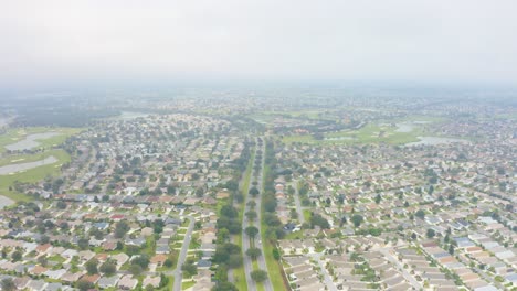 Aerial-drone-shot-rising-about-the-streets-and-myriad-houses-of-The-Villages,-Florida-on-a-foggy-day
