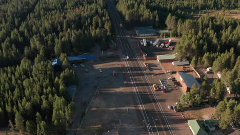 Aerial-shot-over-truck-passing-through-small-highway-village-pan-up-to-Oregon-wilderness