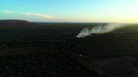 Aerial-panoramic-overview-of-smoke-rising-from-burn-pit-in-middle-of-desert,-northside-curacao