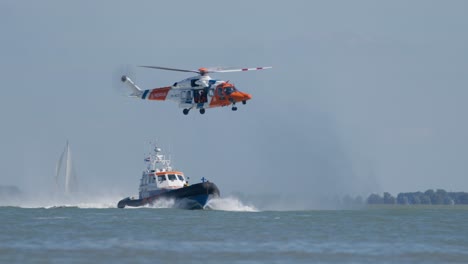 Dutch-Coast-Guard-in-Action,-Helicopter-Flying-Above-Lifeboat-at-Sea