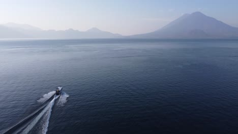 Aerial-follows-tourism-tour-boat-on-Lake-Atitlan,-GTM-volcano-mountain