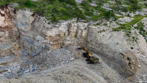 Excavator-parked-in-a-quarry-with-rocks-dug-from-the-side-of-the-mountain