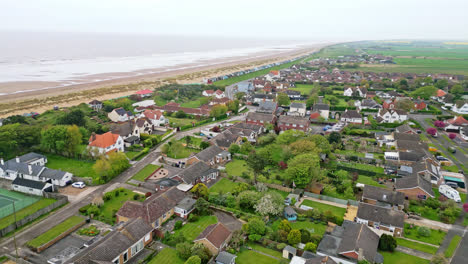 Marvel-at-Mablethorpe's-seaside-landscape-in-aerial-footage,-featuring-beach-huts,-sandy-beaches,-amusement-parks,-rides,-and-the-bustling-tourists