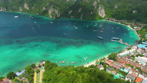 Aerial-view-of-tropical-paradise-beach-in-Thailand-drone-reveals-koh-phi-phi-island-in-krabi-province-thai-famous-holiday-travel-destination,-sail-boat-moored-at-bay-prostine-clear-water