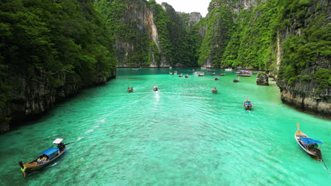 Diving-trip-with-traditional-boats-in-majestic-mountain-bay,-Phi-Phi-islands,-Thailand
