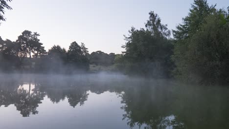 Mist-is-curling-up-on-the-pond-on-sunrise-in-Thetford,-Norfolk,-UK