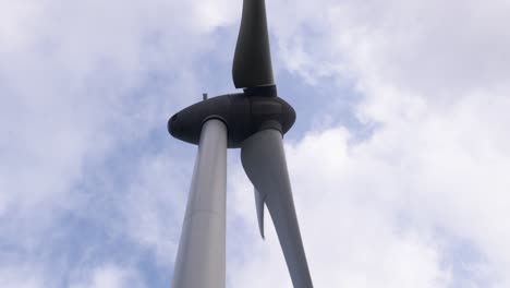 Handheld,-blue-sky-low-angle-shot-of-a-wind-turbine-rotating-in-the-wind