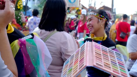 A-lady-holding-a-makeup-palette-while-the-other-person-puts-makeup-on-the-parade-participants