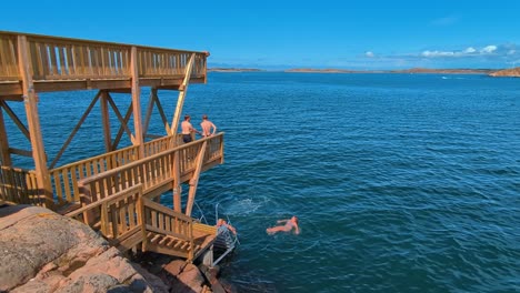 Swimmers-using-the-new-wooden-jump-tower-in-Lysekil,-Sweden